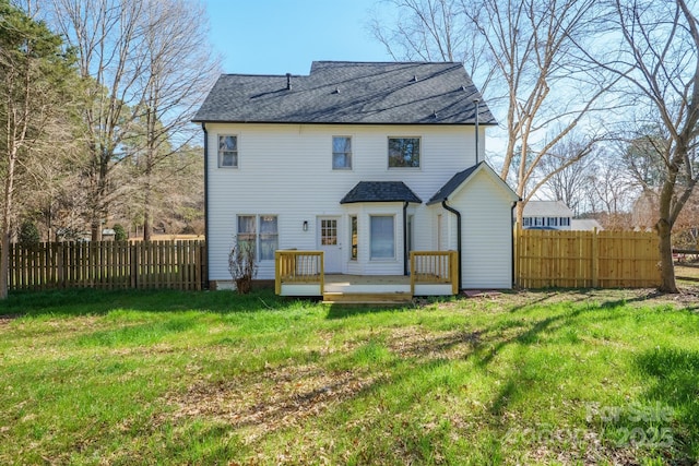 rear view of property featuring a lawn, a fenced backyard, and a wooden deck