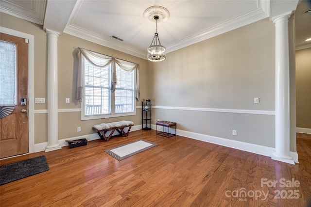 interior space with ornamental molding, wood finished floors, and decorative columns