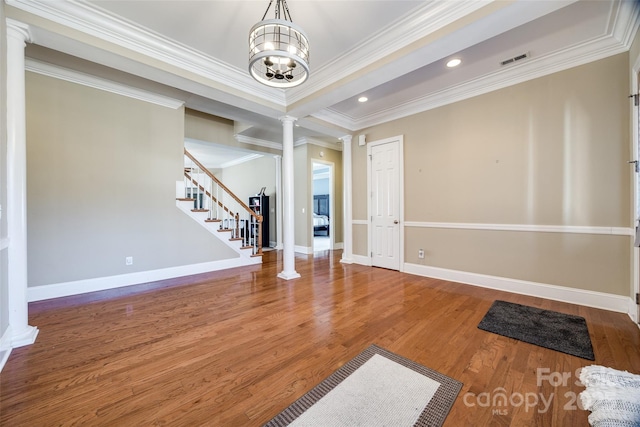 interior space with wood finished floors, visible vents, baseboards, stairway, and decorative columns