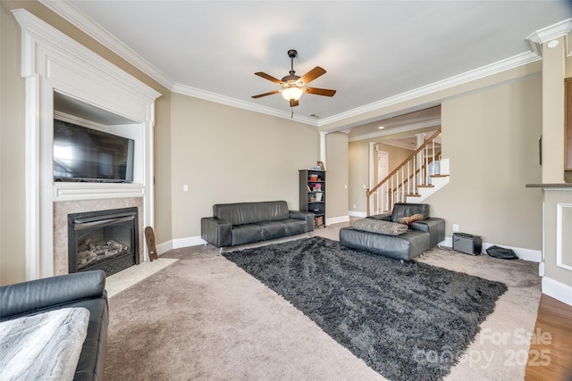 living room with stairs, baseboards, a fireplace with flush hearth, and crown molding