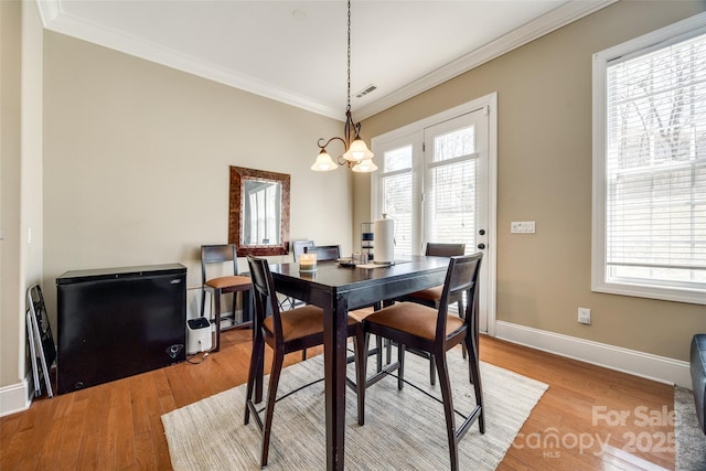 dining room with light wood-style flooring, visible vents, and crown molding