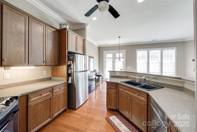 kitchen featuring light countertops, appliances with stainless steel finishes, brown cabinetry, and a sink