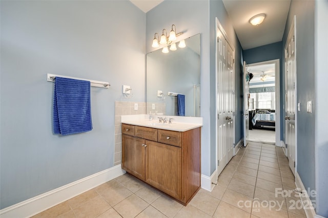 ensuite bathroom featuring tile patterned flooring, connected bathroom, vanity, and baseboards