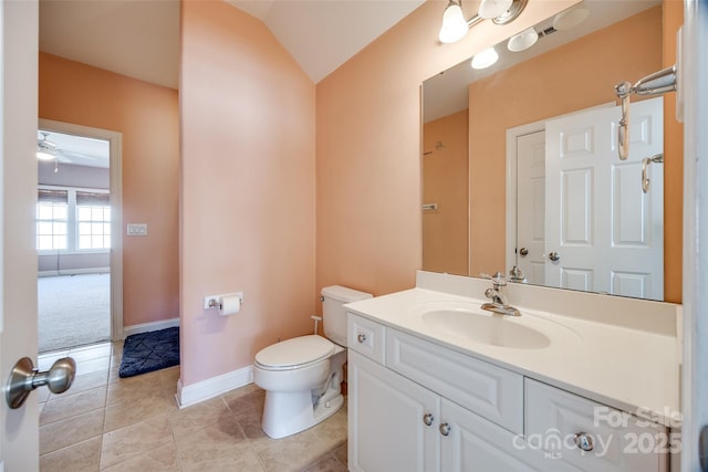 bathroom featuring baseboards, toilet, tile patterned floors, vaulted ceiling, and vanity