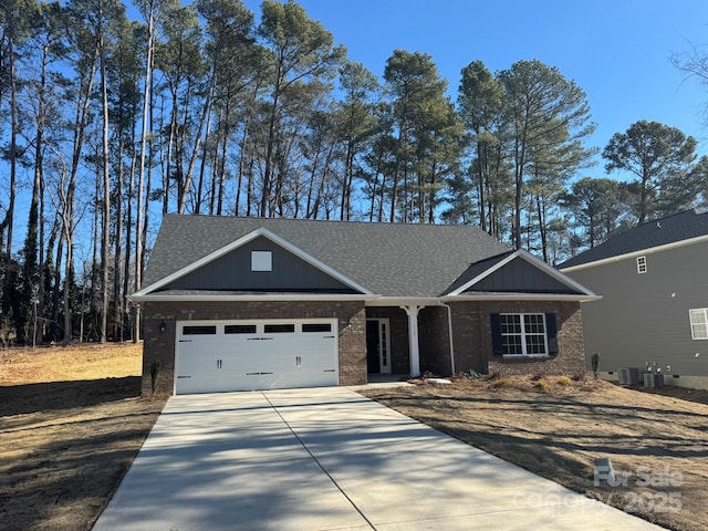 view of front of property with driveway, central AC unit, roof with shingles, an attached garage, and brick siding