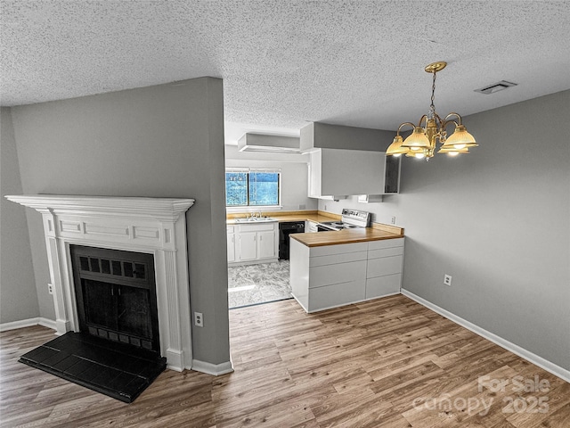 kitchen with light wood-style flooring, a peninsula, visible vents, electric range oven, and dishwasher