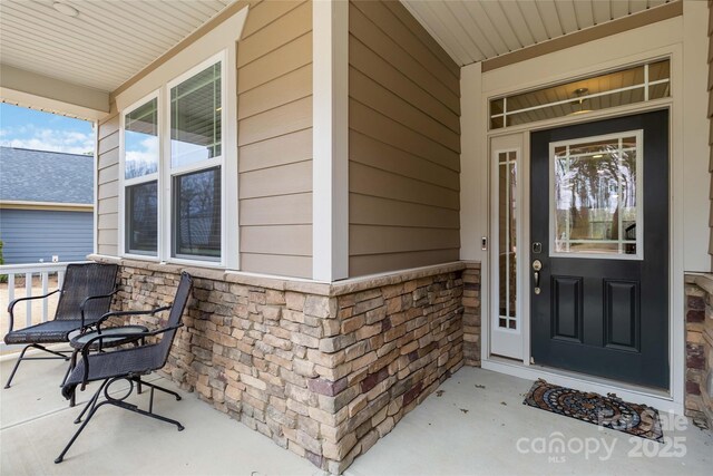 view of exterior entry with covered porch and stone siding