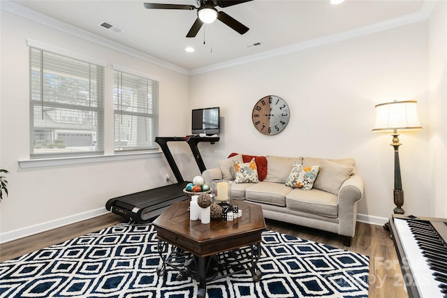 living room with baseboards, visible vents, crown molding, and wood finished floors