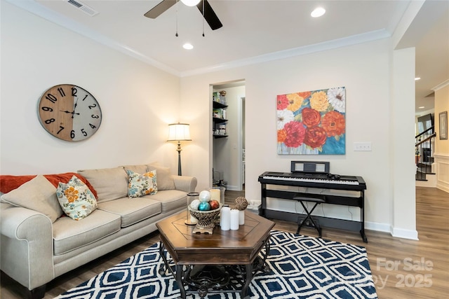 living area featuring baseboards, visible vents, crown molding, and wood finished floors