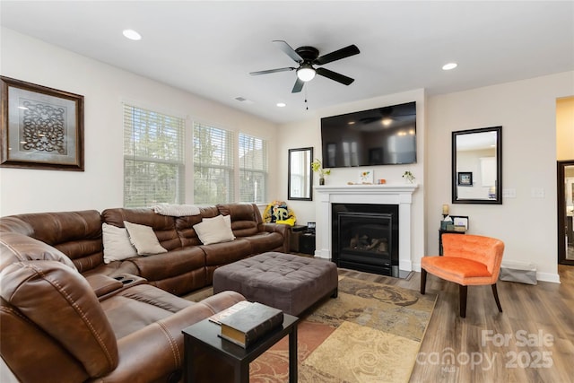 living room with recessed lighting, a glass covered fireplace, baseboards, and wood finished floors