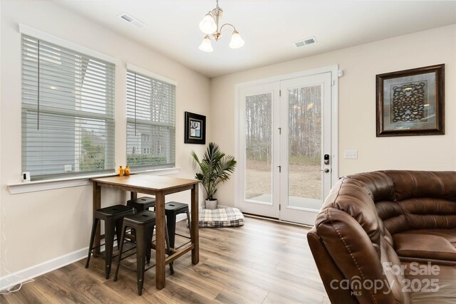 dining room with baseboards, visible vents, a chandelier, and wood finished floors