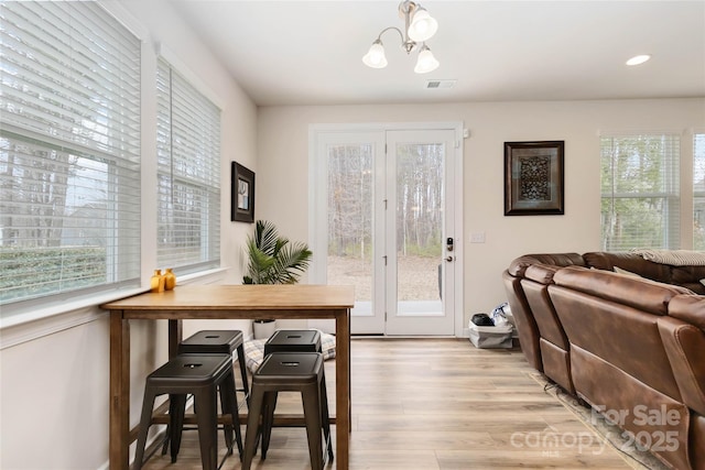 dining space with light wood-style floors, recessed lighting, visible vents, and an inviting chandelier