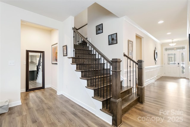 stairway featuring ornamental molding, recessed lighting, wainscoting, and wood finished floors