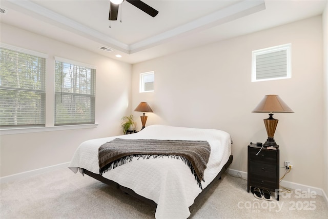 carpeted bedroom with ceiling fan, a raised ceiling, visible vents, and baseboards