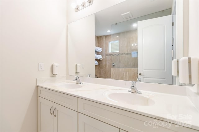 full bath featuring a walk in shower, visible vents, a sink, and double vanity