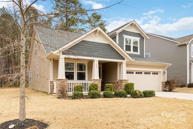 craftsman-style home with an attached garage, roof with shingles, covered porch, stone siding, and driveway