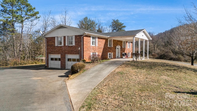 raised ranch with a garage, brick siding, driveway, and a front lawn