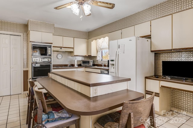 kitchen featuring black microwave, light tile patterned floors, oven, dark countertops, and cooktop