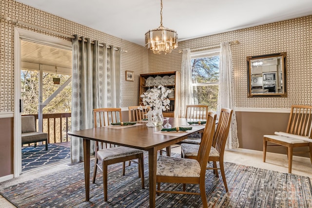 dining space with carpet floors, wallpapered walls, baseboards, and a notable chandelier