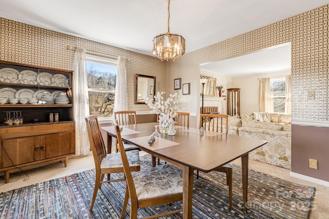 dining room with wallpapered walls, plenty of natural light, a notable chandelier, and light colored carpet