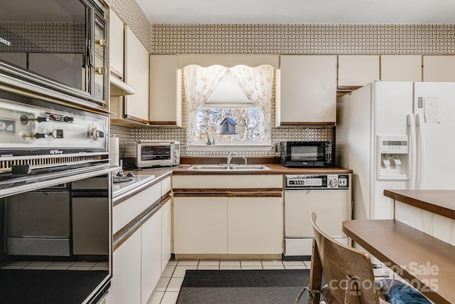 kitchen featuring a toaster, light tile patterned floors, tasteful backsplash, a sink, and white appliances