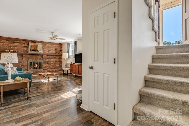 stairway with a healthy amount of sunlight, brick wall, a fireplace, and hardwood / wood-style floors