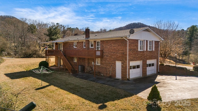 back of property featuring brick siding, concrete driveway, a lawn, a garage, and cooling unit