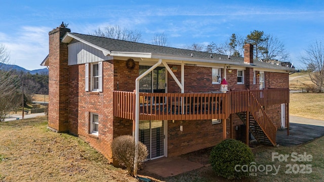 rear view of house featuring a deck, stairway, brick siding, and a chimney