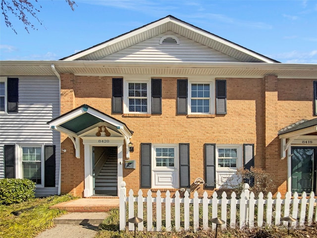 view of front facade featuring brick siding and fence