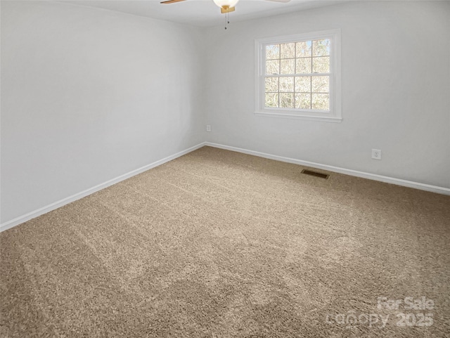 unfurnished room with carpet floors, baseboards, visible vents, and ceiling fan