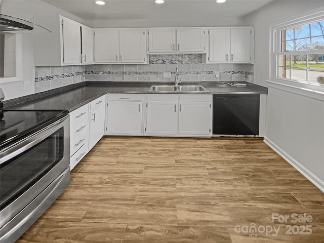 kitchen featuring dishwasher, dark countertops, stainless steel range with electric cooktop, wall chimney range hood, and a sink