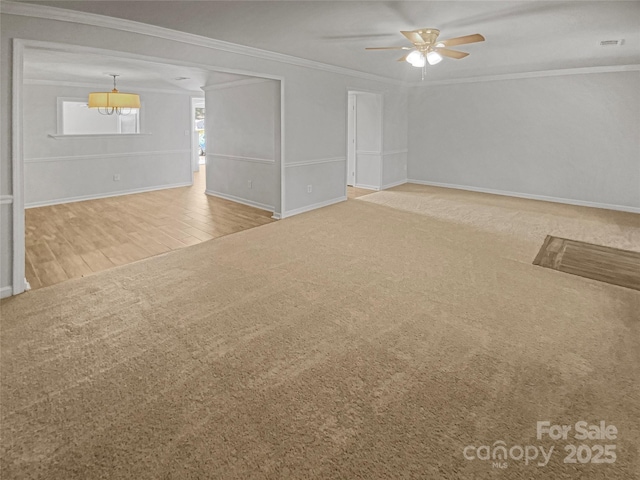 unfurnished living room featuring carpet, baseboards, ceiling fan, and crown molding