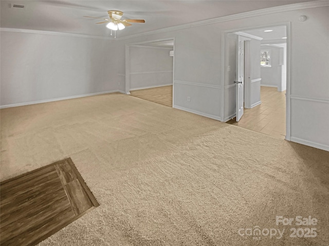 spare room with carpet floors, ceiling fan, baseboards, and crown molding