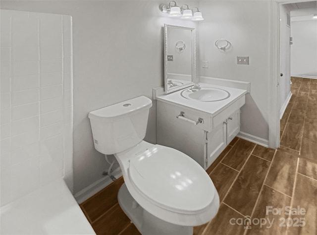 bathroom featuring toilet, wood finish floors, vanity, and baseboards