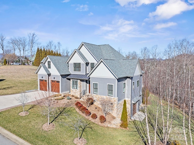 view of front of house featuring stone siding, a standing seam roof, metal roof, and concrete driveway