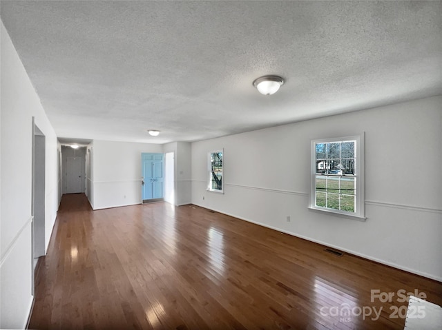 unfurnished room with a textured ceiling, dark wood finished floors, and visible vents