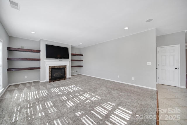 unfurnished living room with visible vents, baseboards, a high end fireplace, tile patterned flooring, and recessed lighting