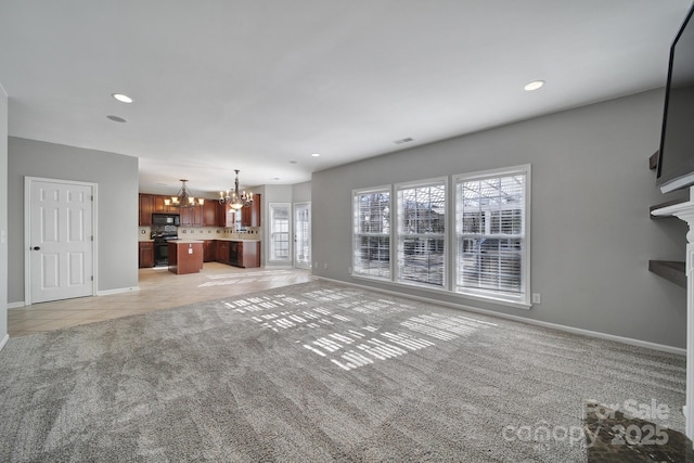 unfurnished living room with light tile patterned floors, light carpet, baseboards, and an inviting chandelier