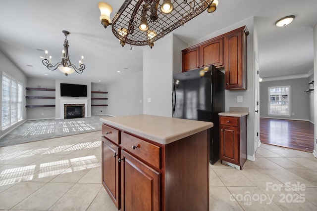 kitchen with light tile patterned floors, plenty of natural light, a glass covered fireplace, and freestanding refrigerator