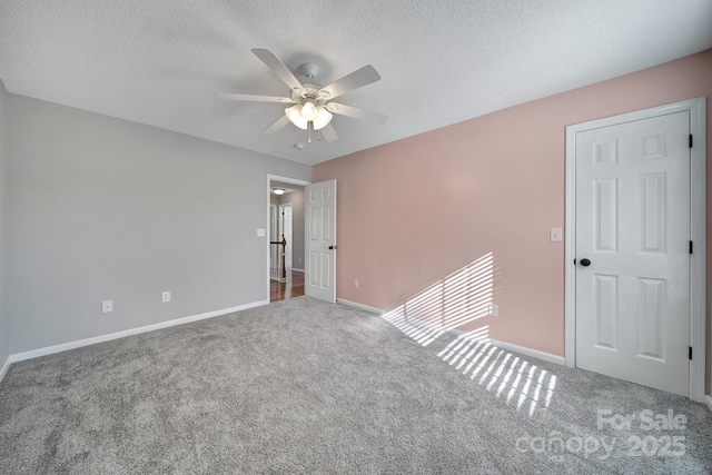 unfurnished room with carpet, baseboards, and a textured ceiling