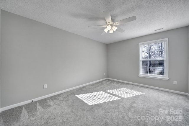 carpeted empty room featuring a ceiling fan, visible vents, a textured ceiling, and baseboards