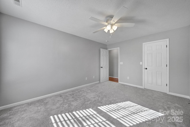 unfurnished bedroom featuring carpet floors, visible vents, a textured ceiling, and baseboards