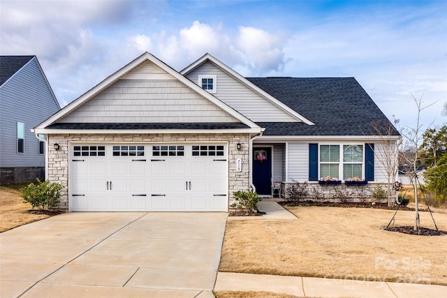 view of front of home with a garage, concrete driveway, a shingled roof, and stone siding