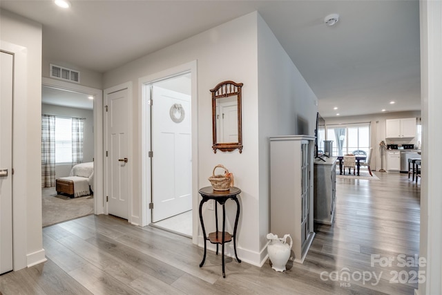 hallway featuring light wood-style floors, recessed lighting, a healthy amount of sunlight, and visible vents