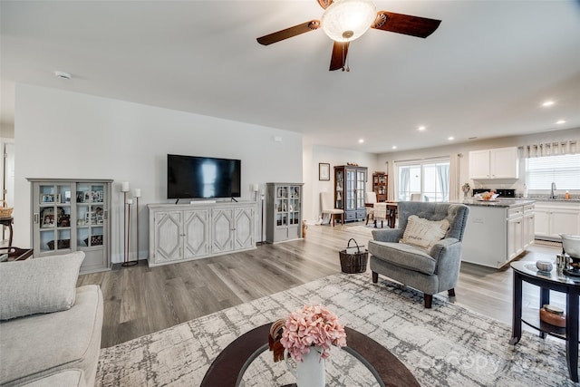 living area featuring recessed lighting, ceiling fan, light wood-style flooring, and baseboards