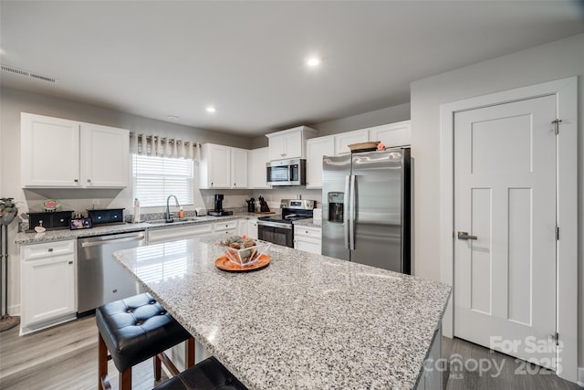 kitchen featuring a center island, visible vents, appliances with stainless steel finishes, white cabinets, and a sink