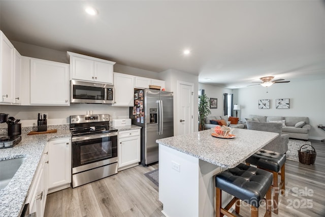 kitchen featuring stainless steel appliances, a center island, light wood-type flooring, and a breakfast bar area