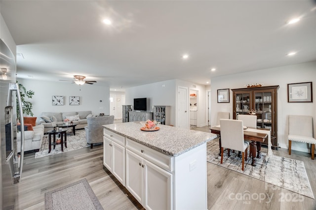 kitchen with ceiling fan, light wood-style flooring, a kitchen island, and white cabinets