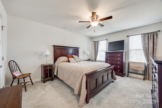 bedroom featuring light carpet, ceiling fan, visible vents, and baseboards