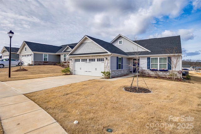 view of front of house with an attached garage, stone siding, concrete driveway, and a front yard